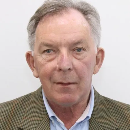 Portrait of an older man with gray hair wearing a brown checkered jacket