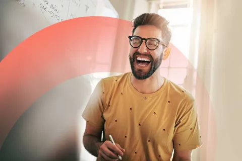 Smiling professional standing by a whiteboard, laughing and engaging during a creative brainstorming session.