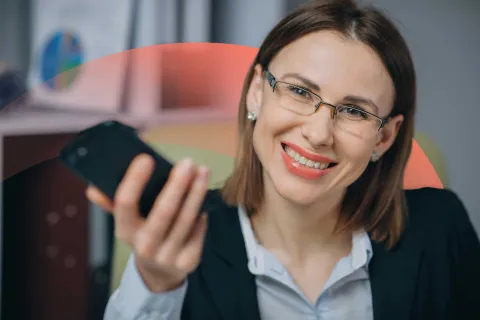 Smiling businesswoman holding a phone, and smiling at the camera.