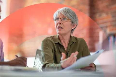 Professional woman speaking to someone, reviewing and holding a paper document.