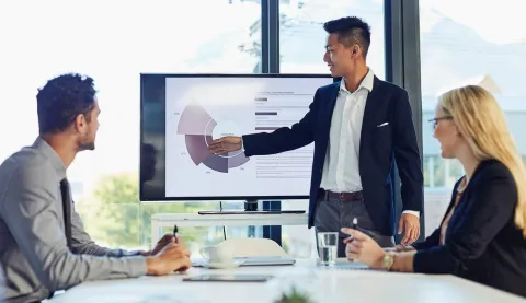 Business meeting with three people discussing charts in a bright office
