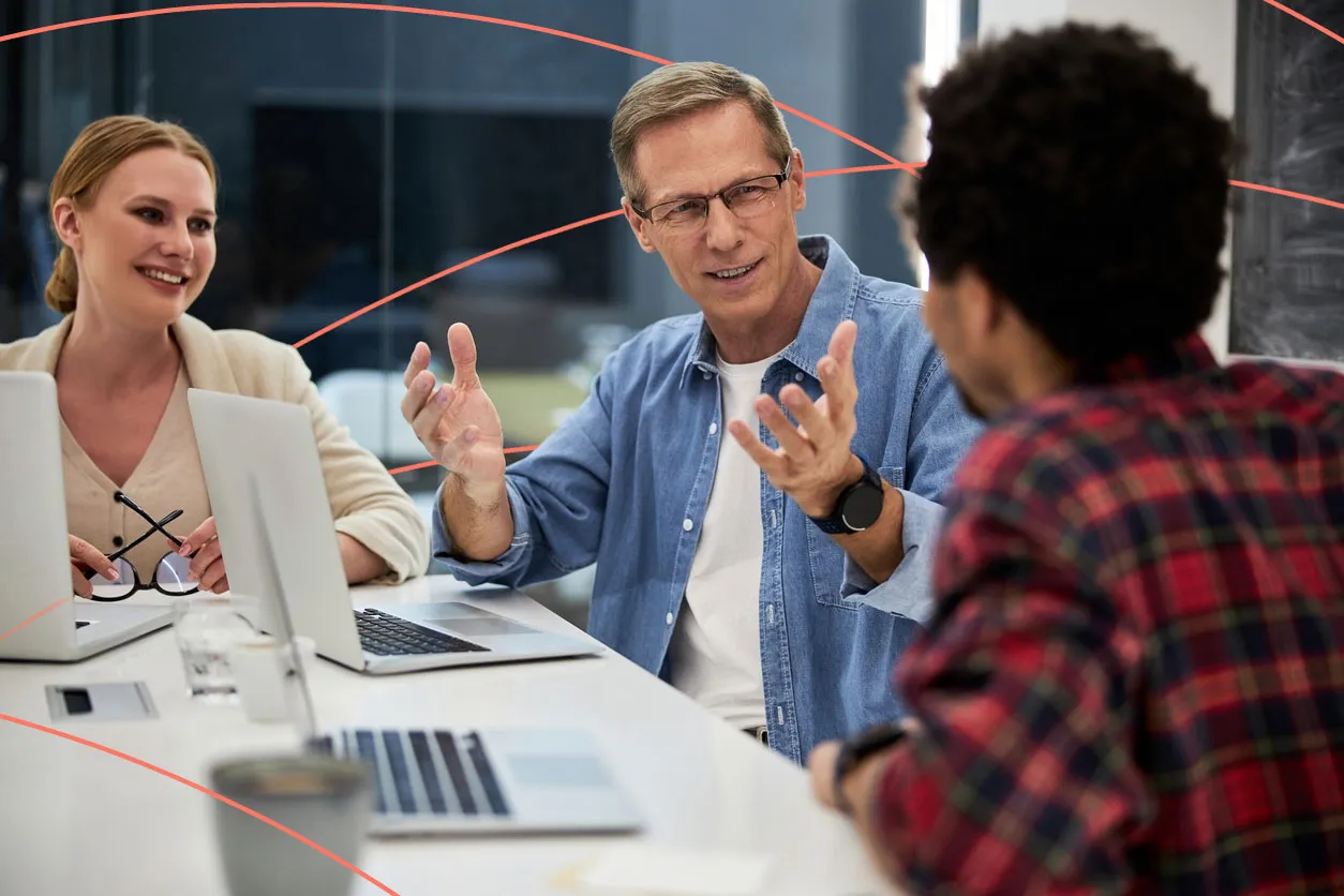 Team of professionals engaged in a discussion around laptops during a business meeting