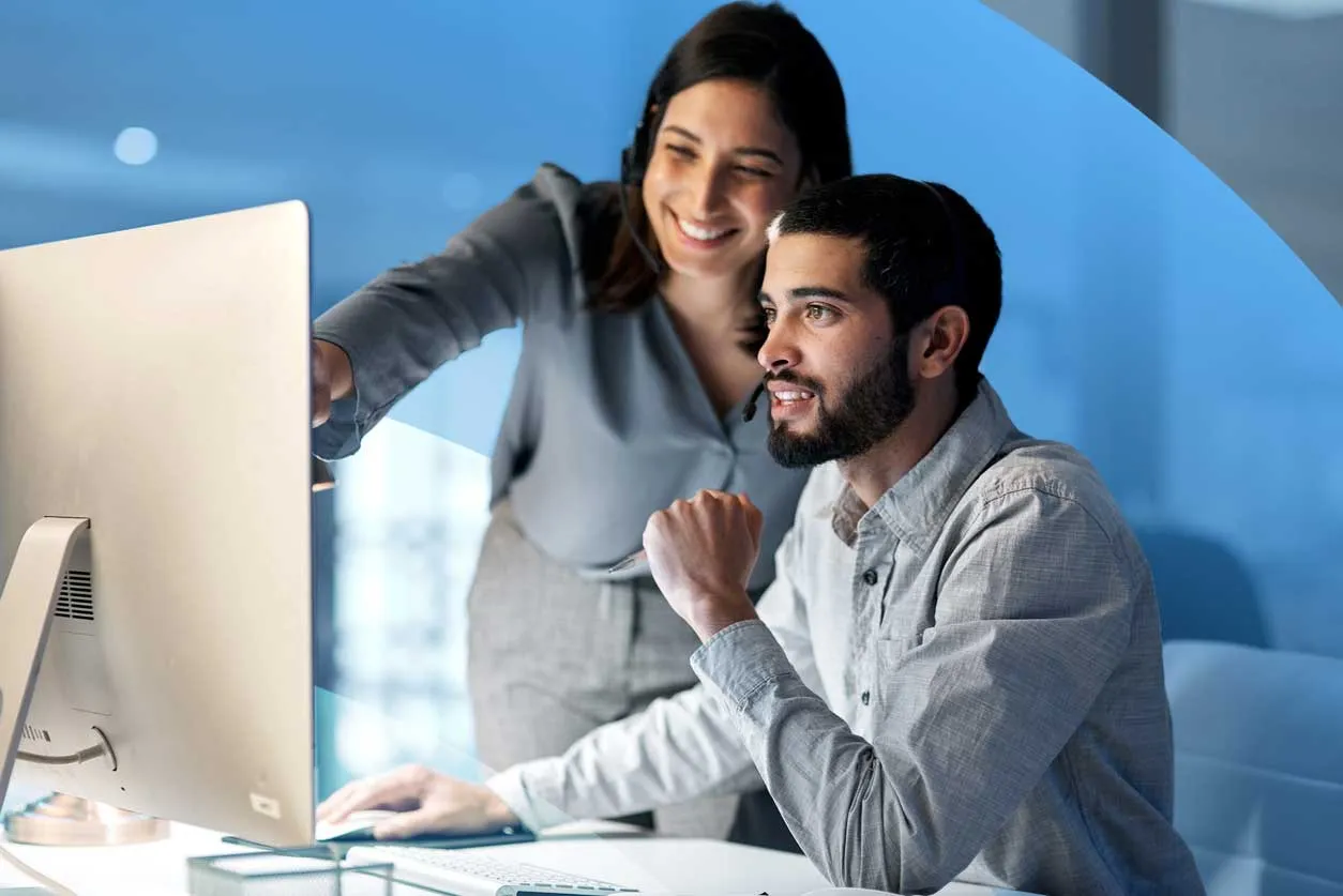 Two professionals collaborating at a computer, reviewing data and working together in an office.