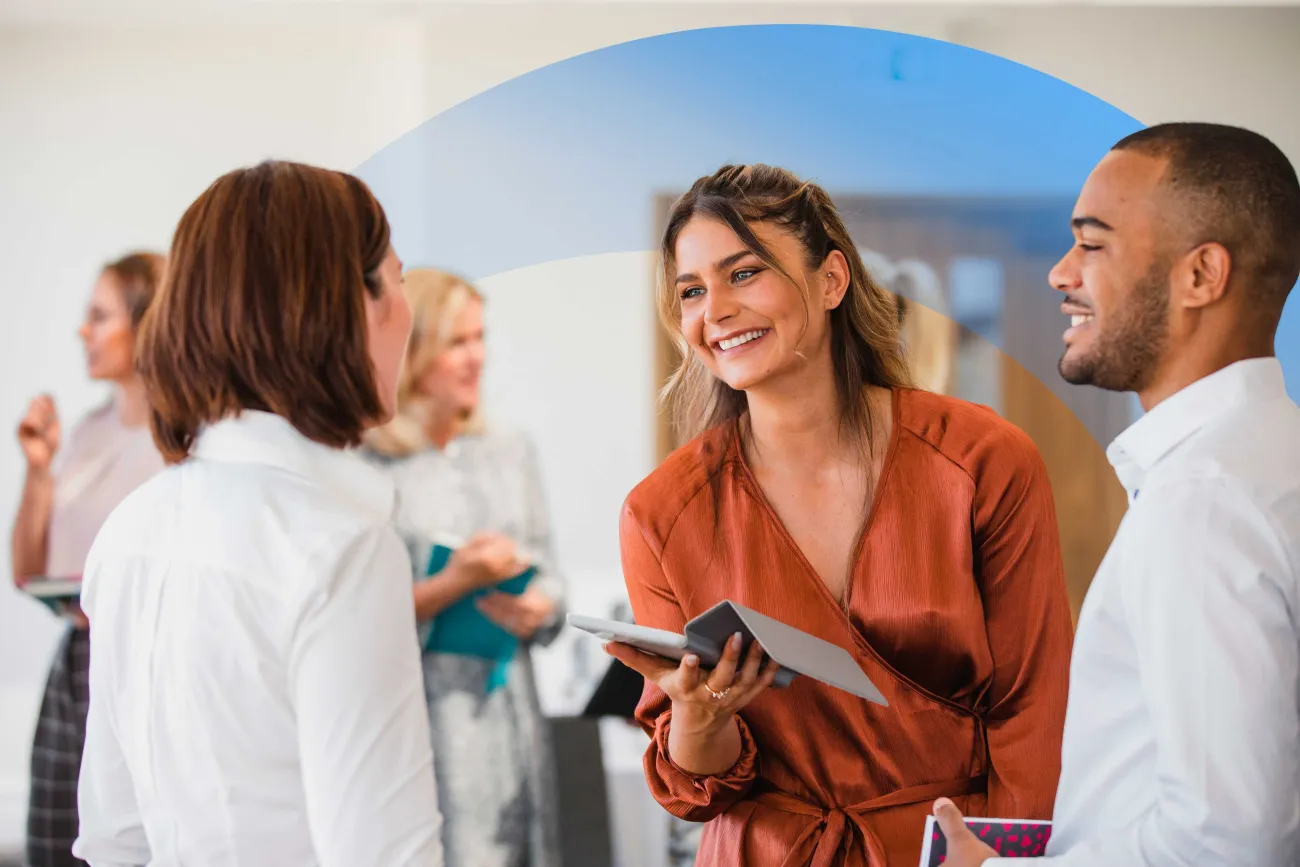 Colleagues smiling to each other, while holding notebooks and tablets.