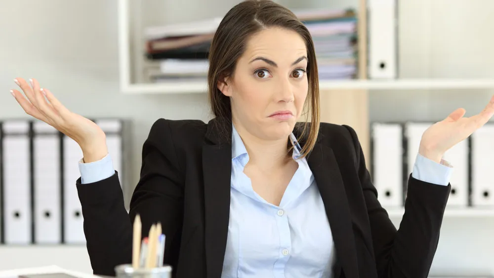 A brown-haired girl shrugging in confusion. She's wearing an open suit jacket and white shirt.