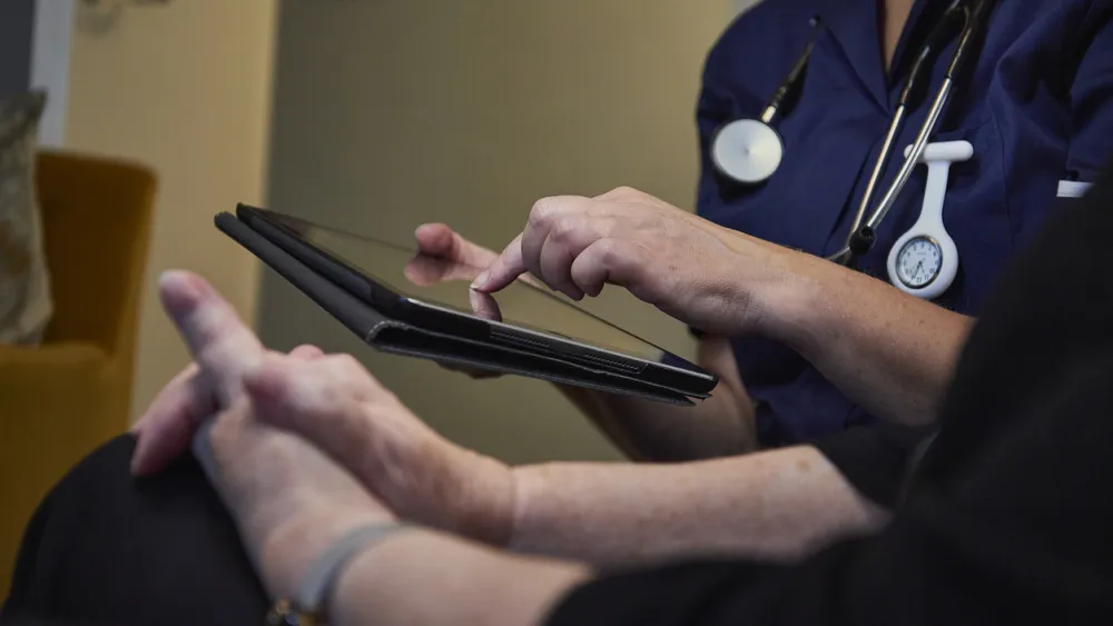 Doctor in blue scrubs using a tablet with a patient