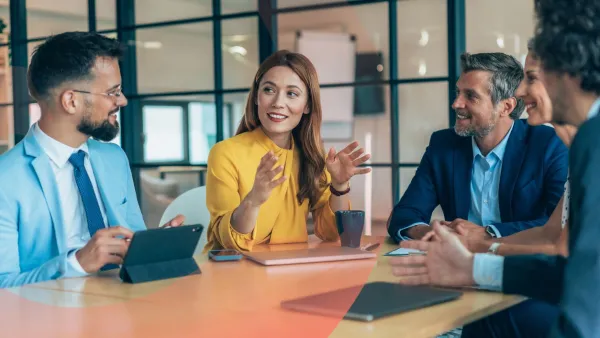 Four professionals sitting around a table, with one woman leading the discussion while others listen and smile.