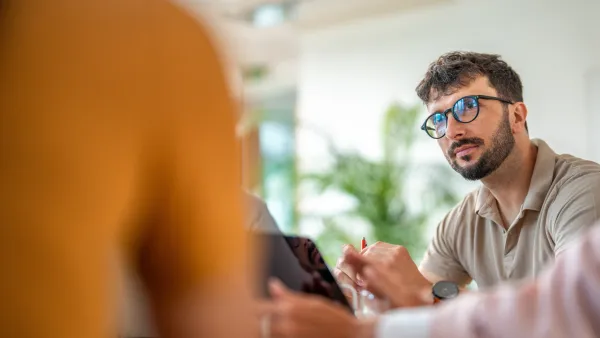 Man wearing glasses attentively listening in a meeting